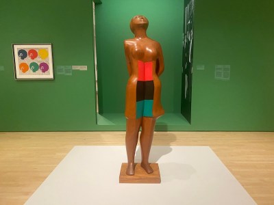 A sculpture of a female figure with swatches of red, black, and green at her center.