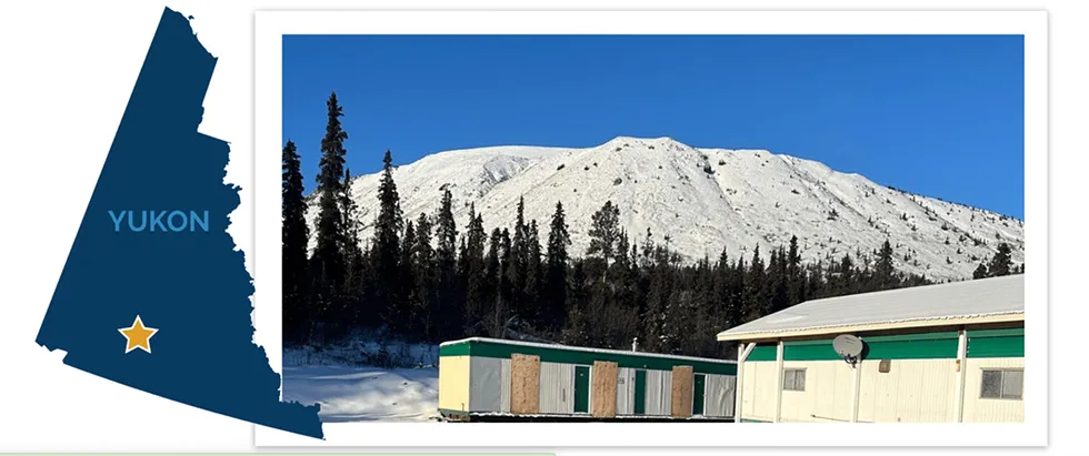 Snowy mountain with trees and cabins in Yukon indicating Blue Jay Gold's location
