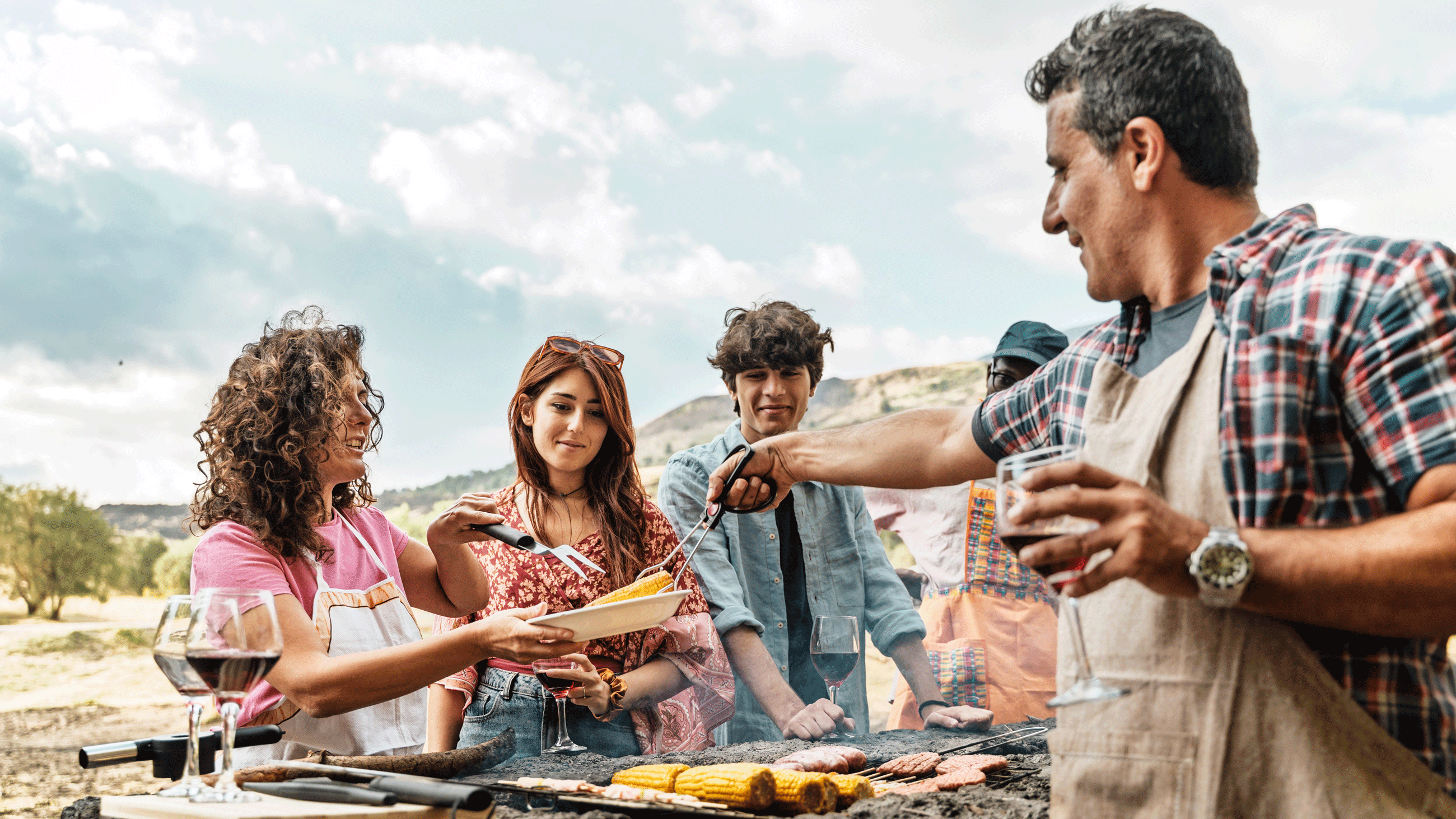 Family barbecuing corn drinking wine