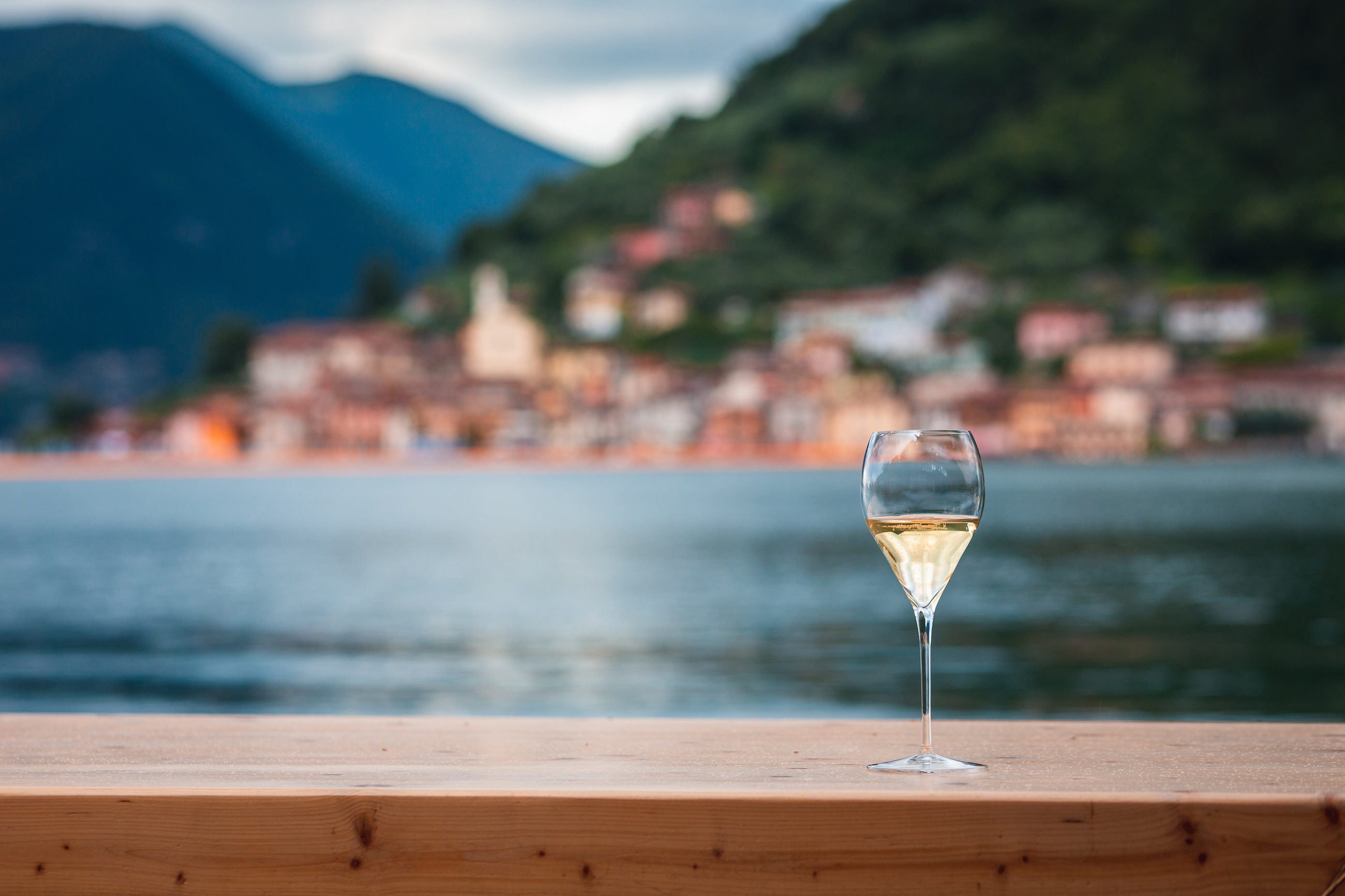 glass of sparkling wine by lake como
