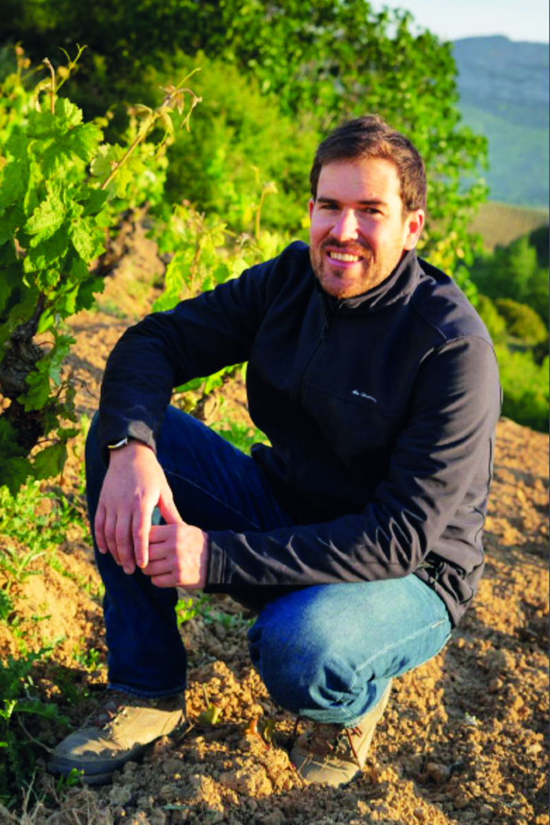 Bryan MacRobert crouched next to a vine