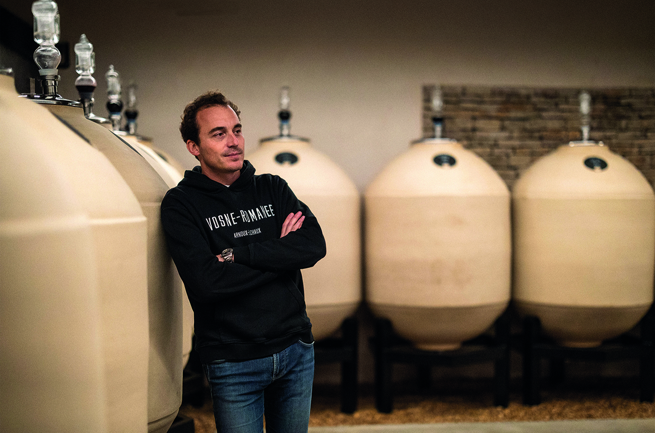 Charles Lachaux standing against sandstone ceramic wine tanks
