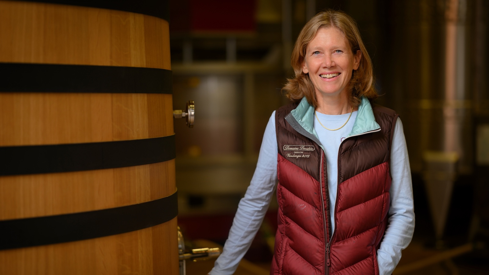 A portrait of Domaine Drouhin Oregon winemaker Véronique Boss-Drouhin standing next to a large, upright wood cask.