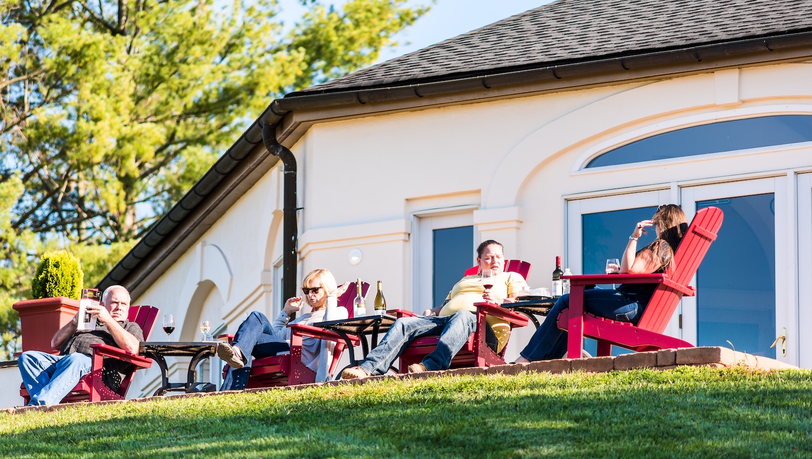 People tasting Virginia wine while sitting in red Adironack chairs outside of Barboursville Vineyards' winery in Charlottesville.