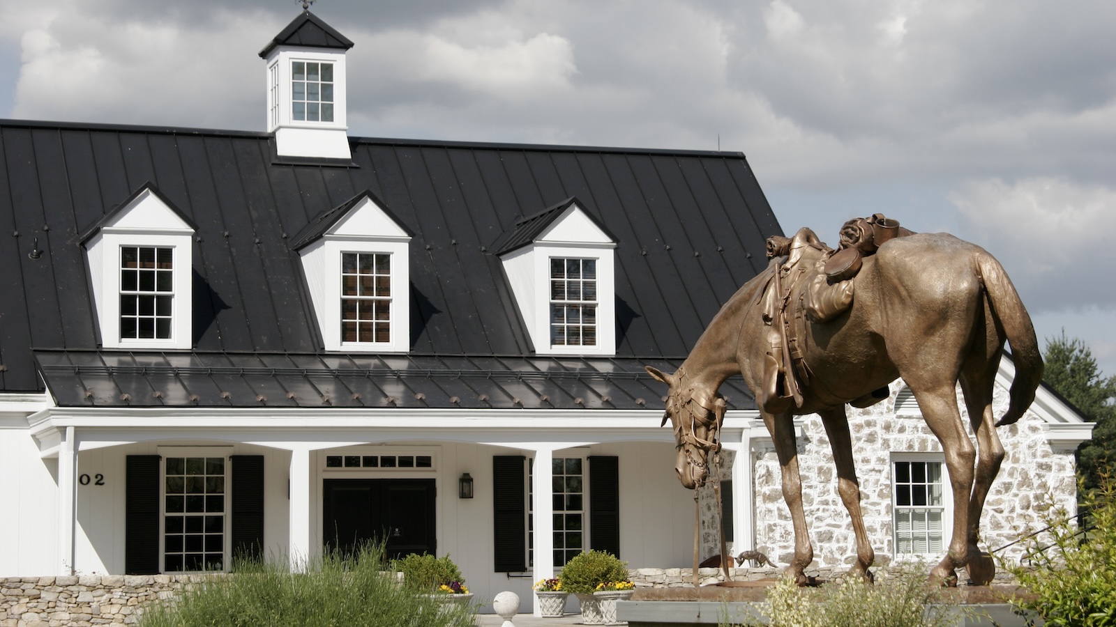 The white barn-like exterior of the National Sporting Library & Museum in Middleburg, with a statue of a riderless, saddled horse out front.